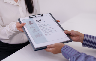 Close-up dello scambio di curriculum tra recruiter e discente durante un colloquio di lavoro