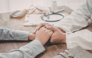 Due mani di persone che si stringono delicatamente in segno di sostegno reciproco, a rappresentare l’economia della cura e del benessere e la relazione di aiuto tra individui.