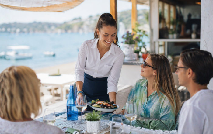 cameriera che serve un piatto di cozze durante un pranzo vista mare